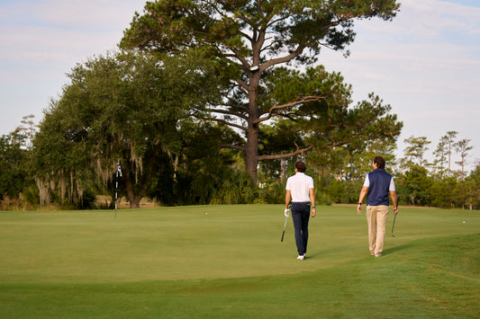 Two golfers walking away on a picturesque golf course.