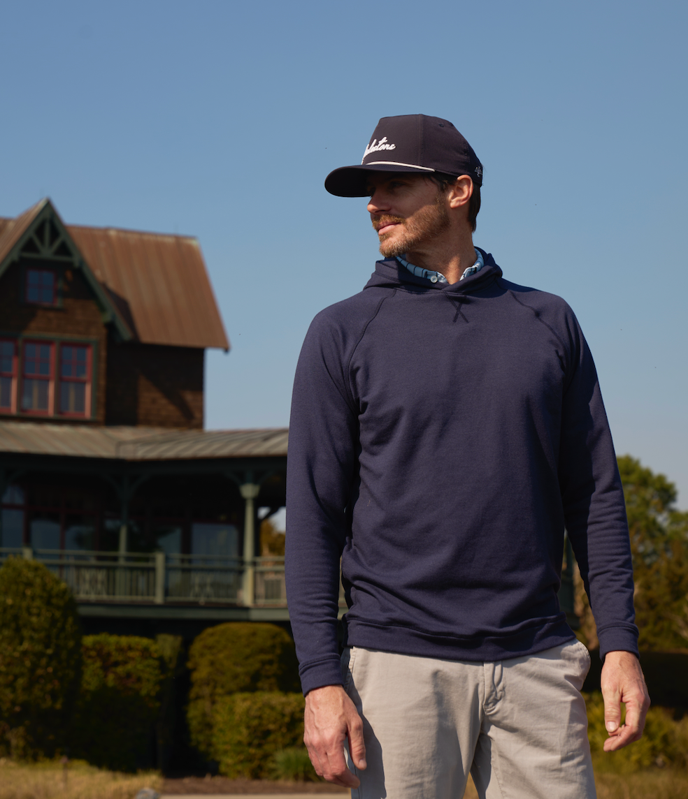 Golfer in formal attire, gazing thoughtfully at a distant golf course.