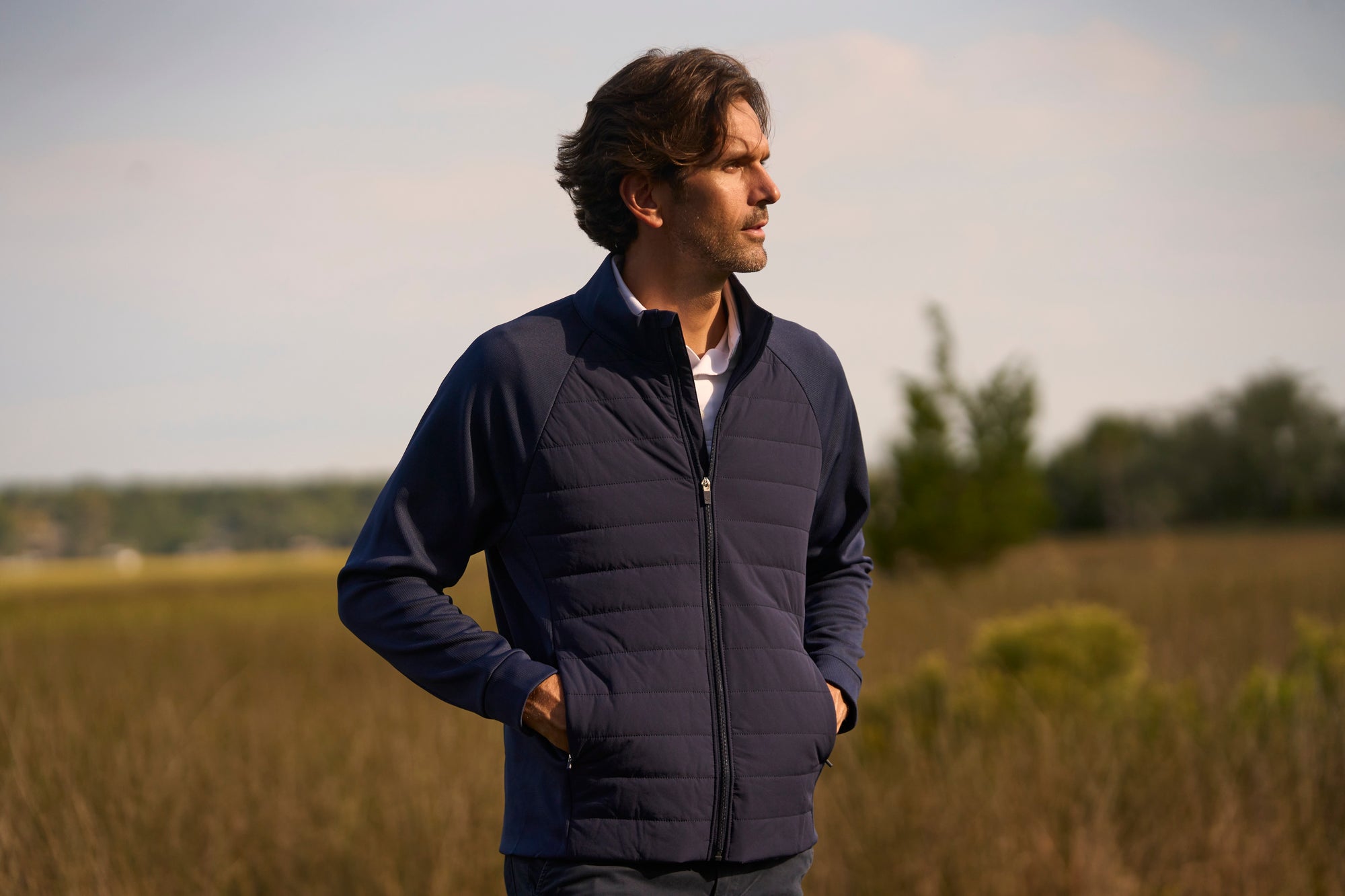 A man strolling through a grassy field with mountains in the distance