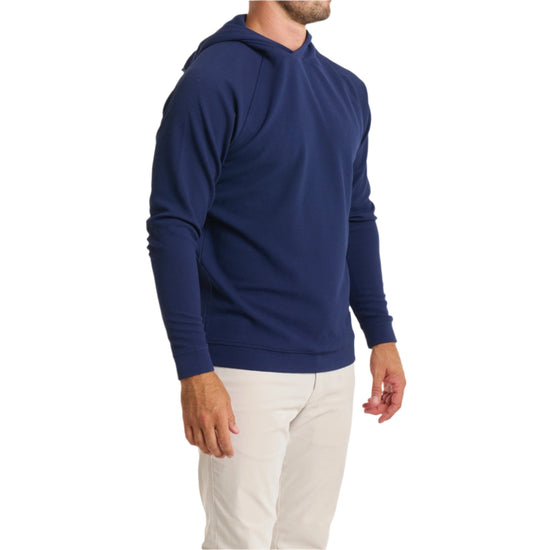 Close-up of a man wearing the Horizon Hoodie in Beaufain Blue with white pants, cropped from chin to knees, against a solid white background.