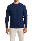 Close-up of a man wearing The Surfside Longsleeve Tee in beaufain blue color with cream white color pants, cropped from chin to knees, against a solid white background.